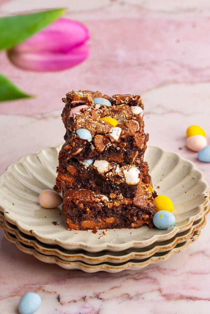 A stack of three brownies with cadbury mini eggs in them on a plate