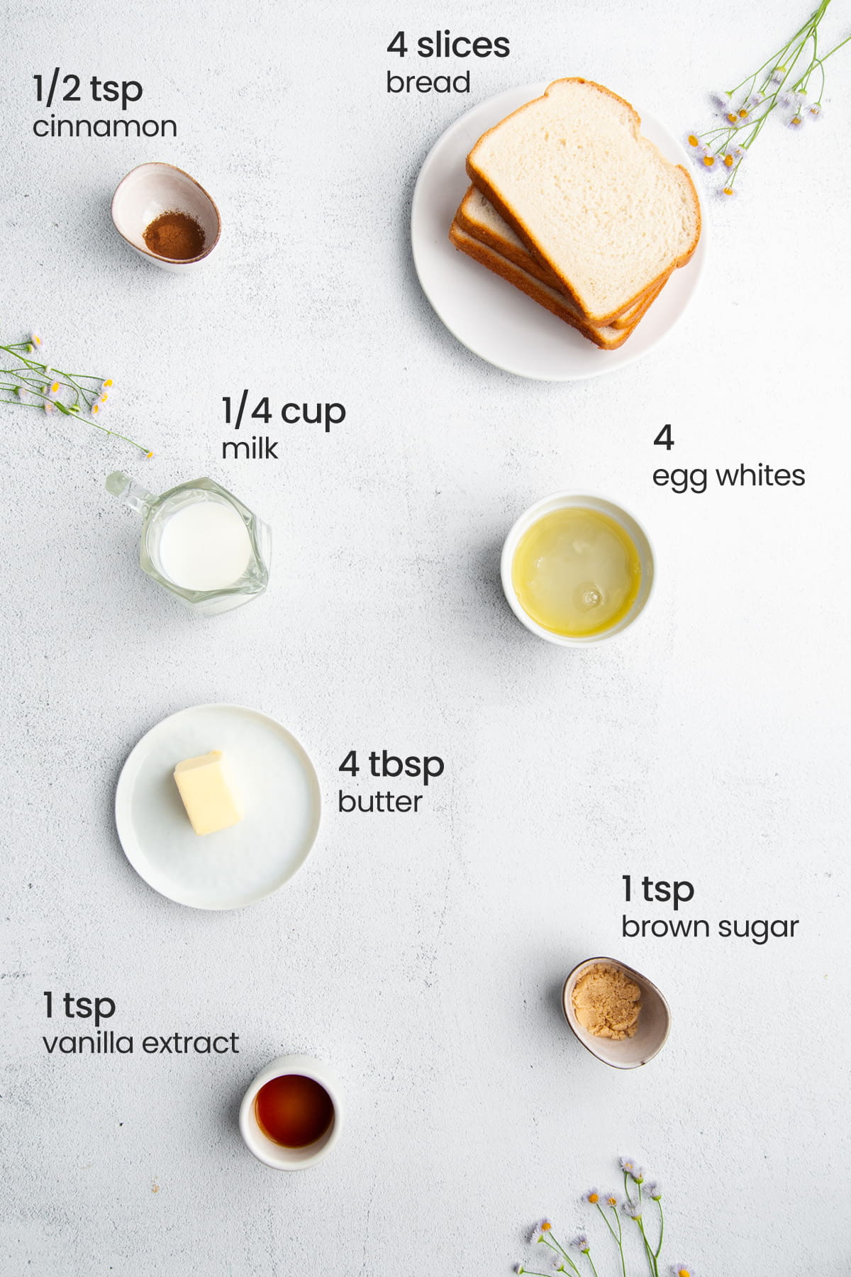 Overhead view of the ingredients for egg white french toast - cinnamon, bread, milk, egg whites, butter, vanilla extract, and brown sugar.