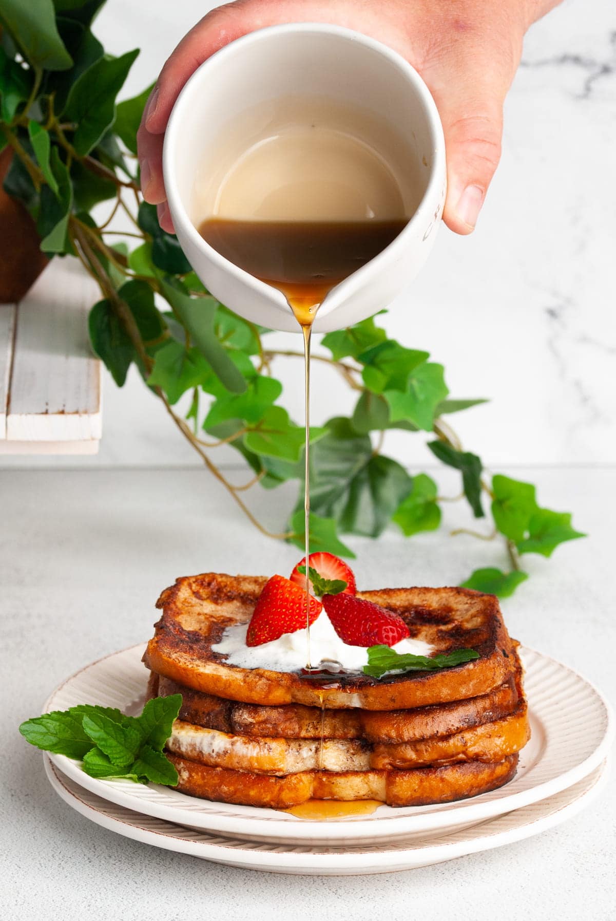 pouring syrup over egg white french toast with strawberry and cream