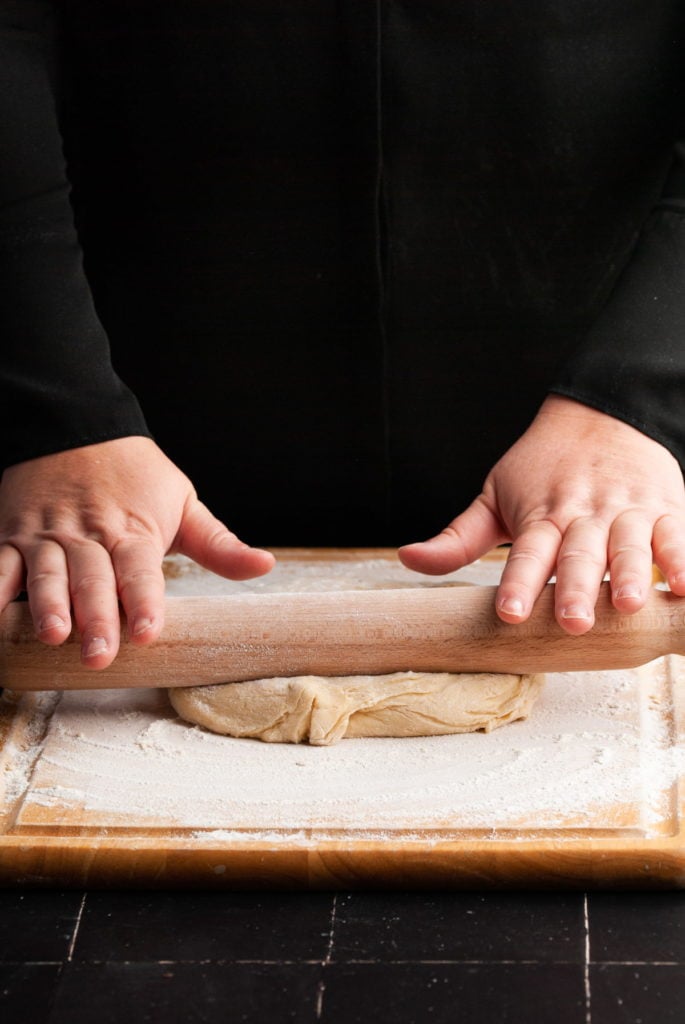 rolling out cinnamon roll dough to prep it for filling