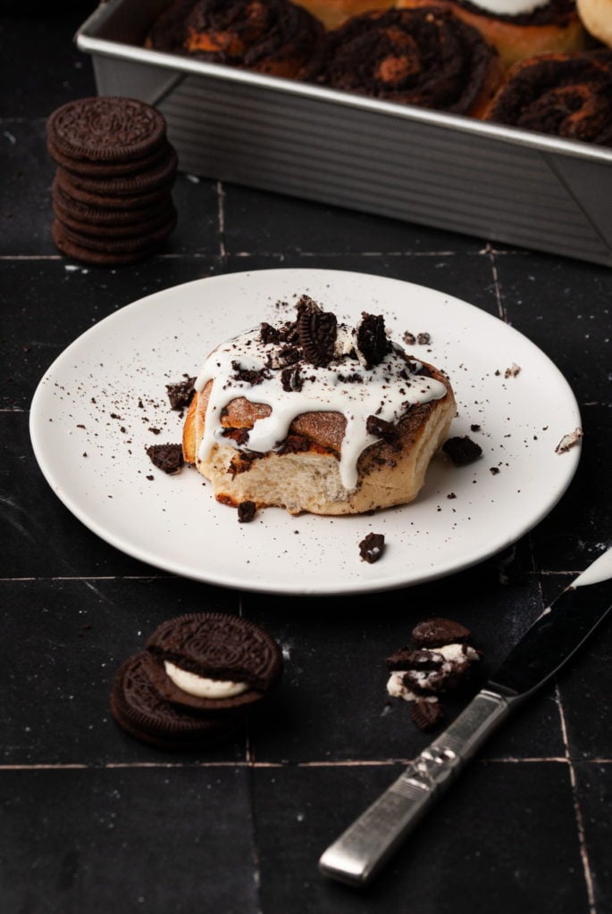 oreo cinnamon roll on a white plate with more crushed oreos on top