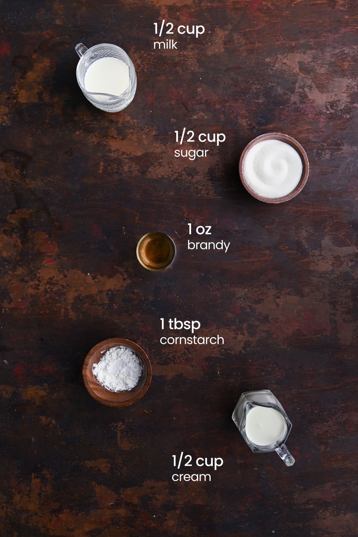 Overhead view of the ingredients needed for brandy sauce for bread pudding - milk, sugar, brandy, cornstarch, and cream.