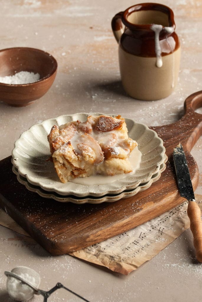 piece of bread pudding on a plate smothered in vanilla sauce