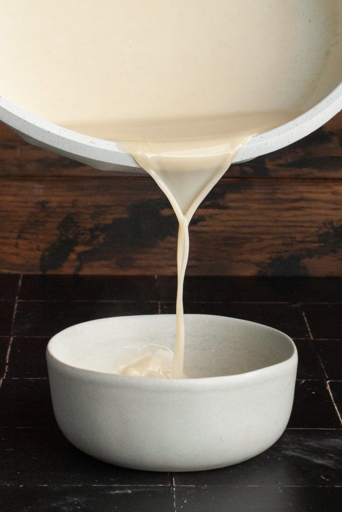 pouring vanilla sauce from hot pan into a bowl to cool