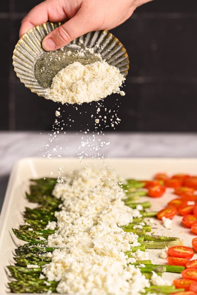 sprinkling parmesan cheese on top of roasted asparagus