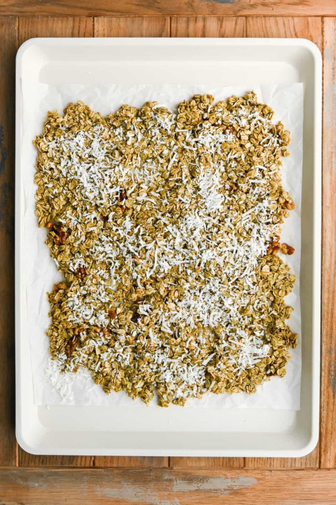 spreading matcha granola out on a baking sheet ready for the oven