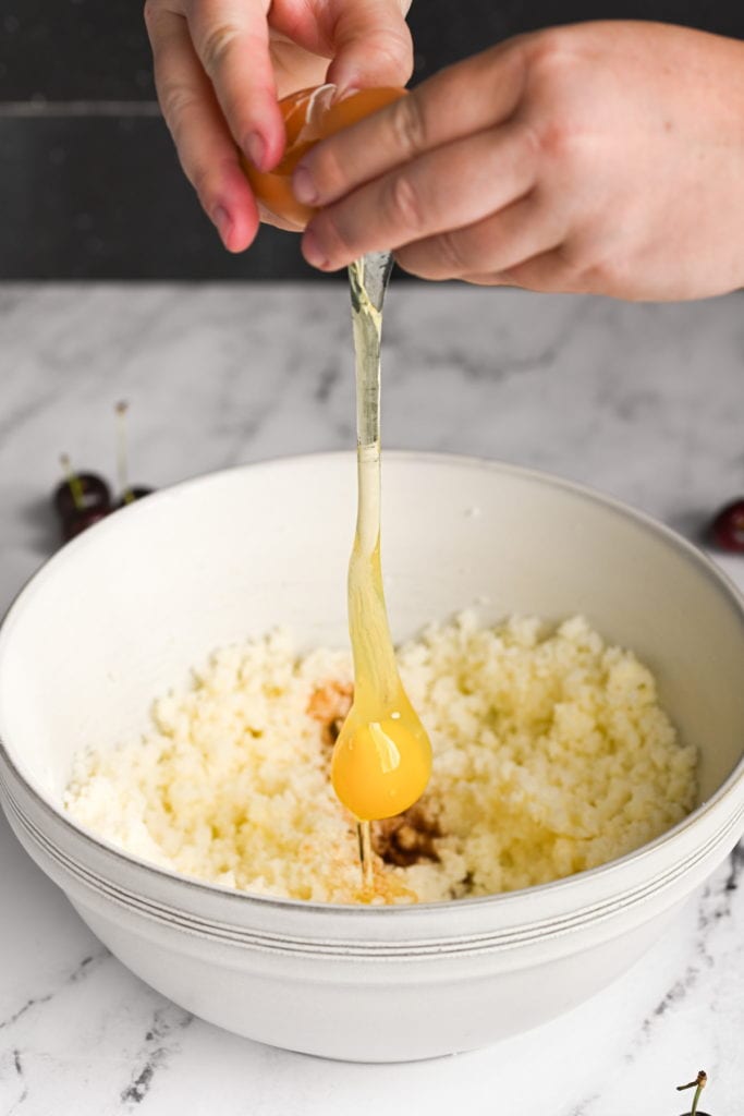 cracking an egg into cherry brownie batter