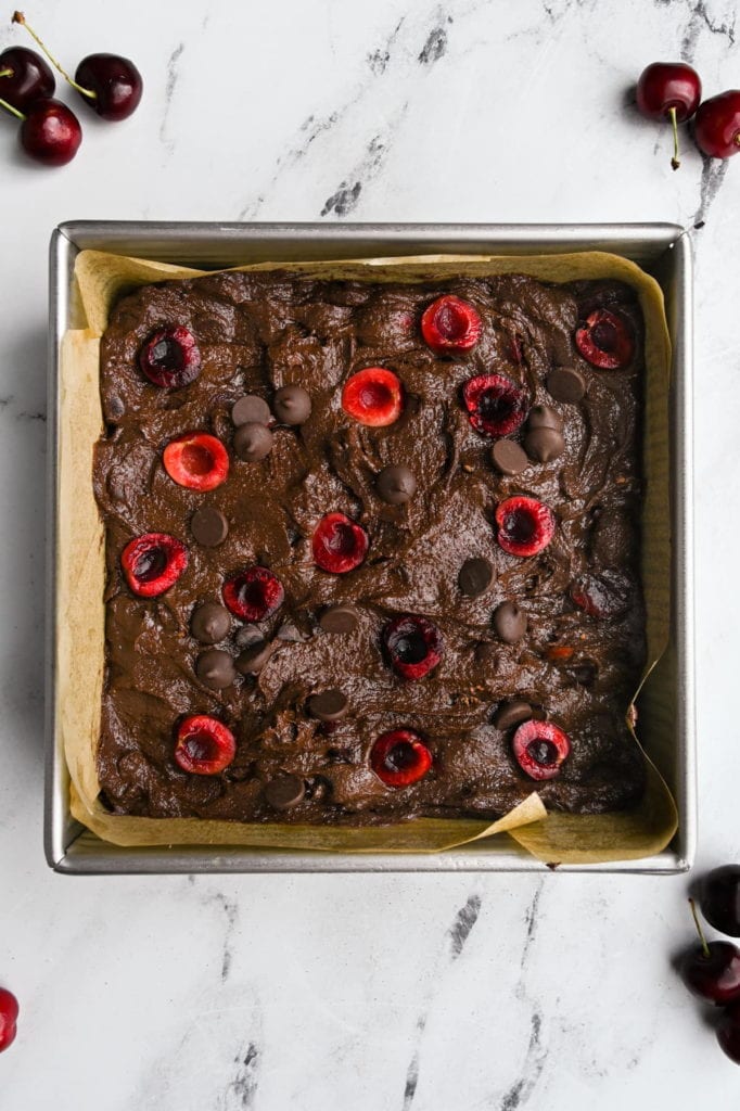 cherry brownie batter in a square baking pan ready for the oven