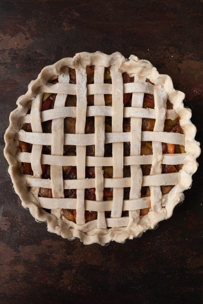 Pinching excess pie dough around the side of pie dish to form outer crust