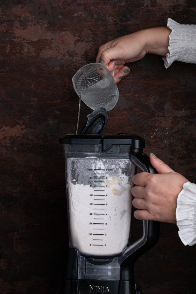 pouring ice cold water into blender to form pie crust