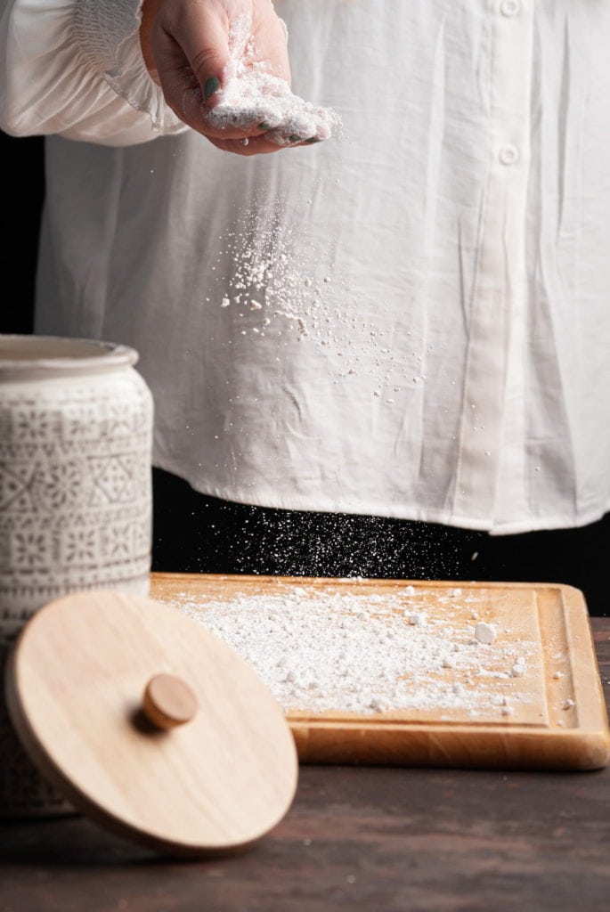 adding flour to a clean surface to roll out dough on