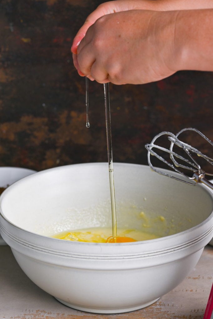 cracking eggs into mixing bowl with consensed milk, butter, and sugar