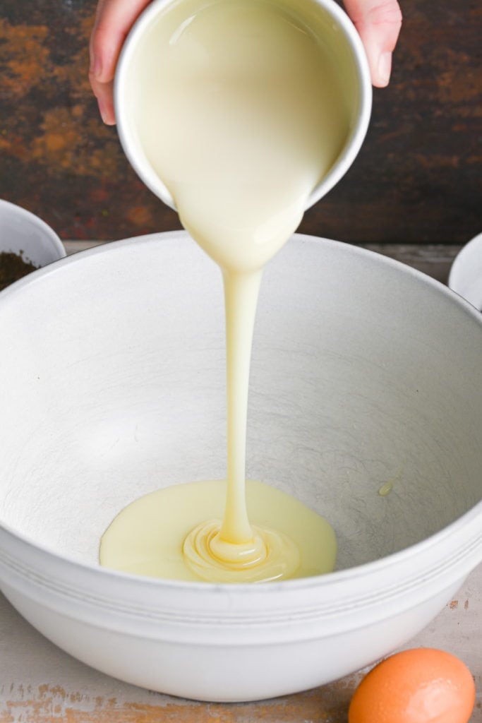 Adding condensed milk to a large mixing bowl
