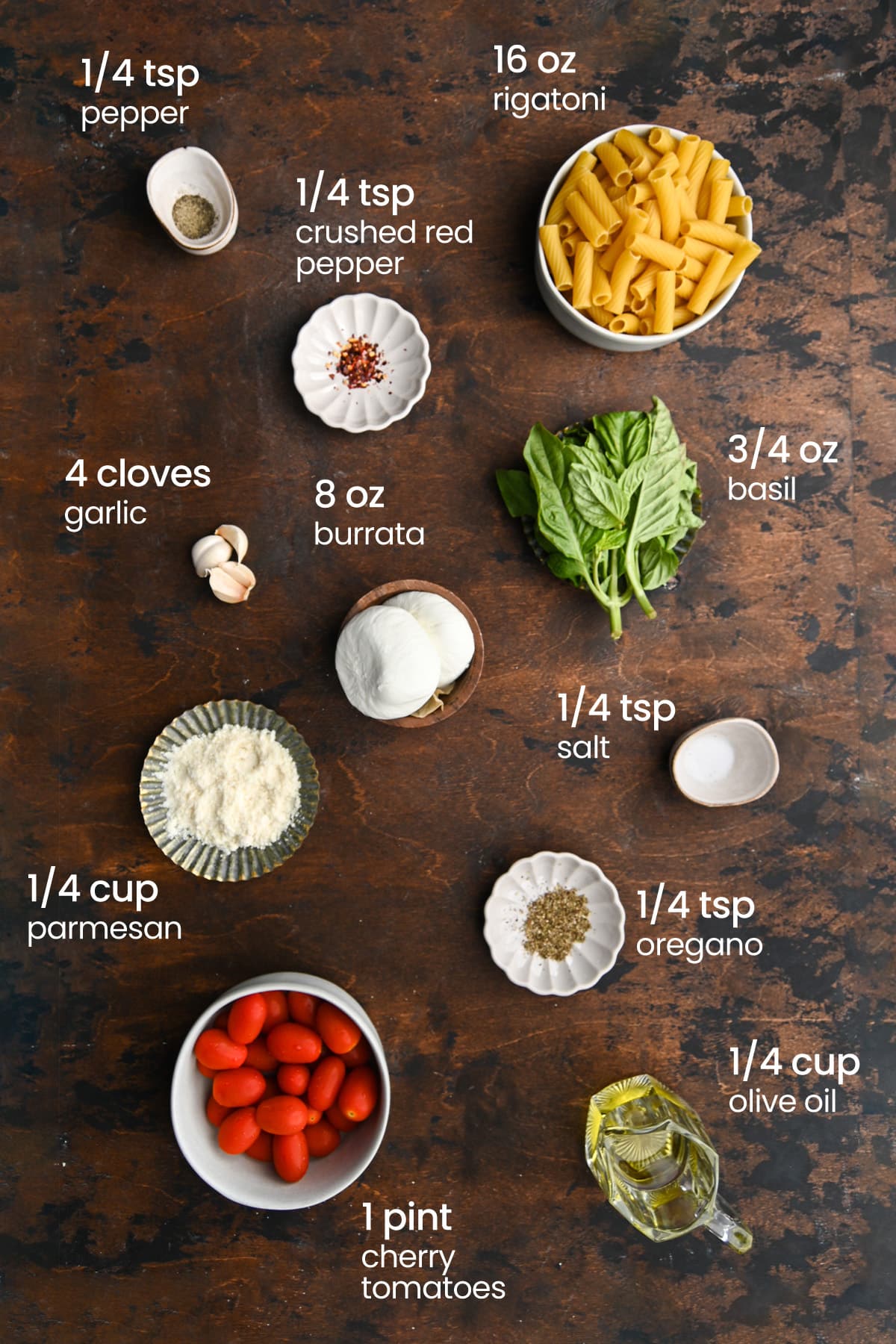 Overhead view of the ingredients needed for rigatoni burrata - Rigatoni, pepper, crushed red pepper, garlic, burrata, basil, parmesan, oregano, salt, olive oil, and cherry tomatoes.