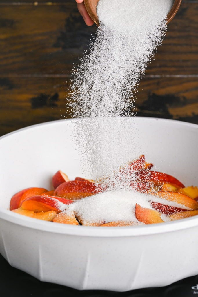 adding sugar to peaches in a pan