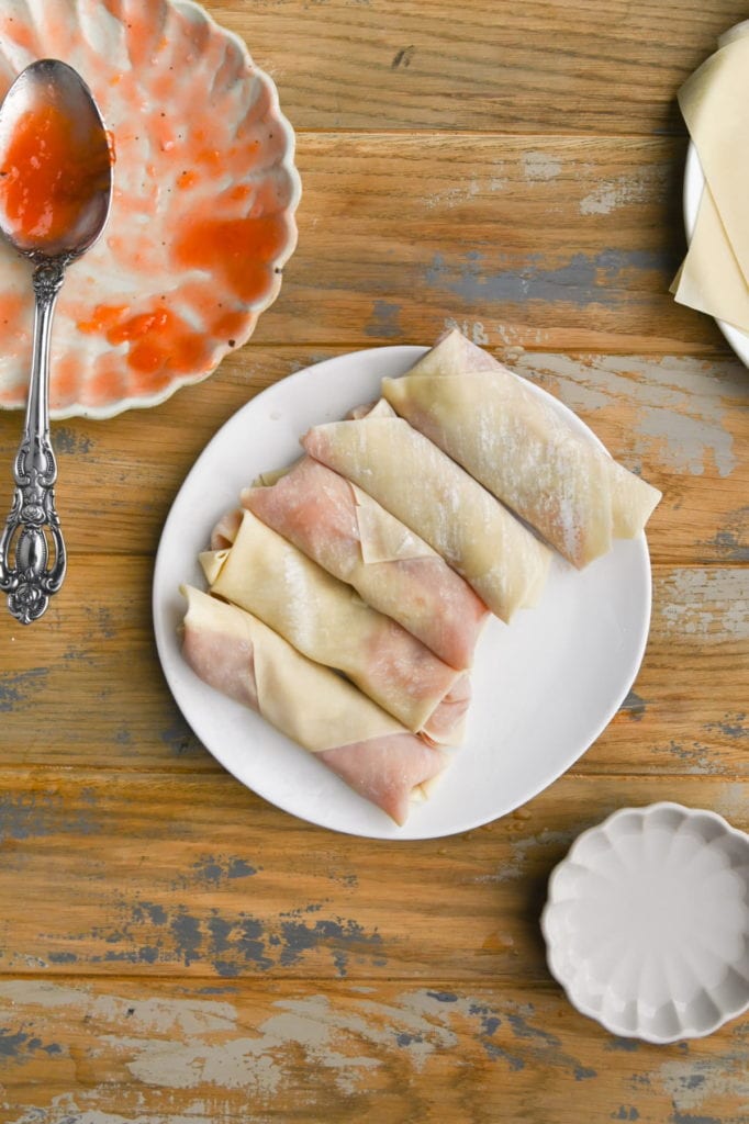 Wrapped peach cobbler egg rolls ready for the fryer.