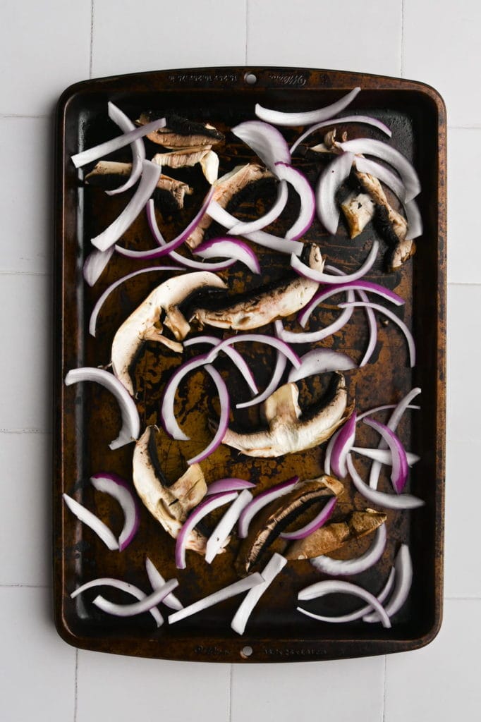 sliced portobello mushrooms and red onion on a sheet pan