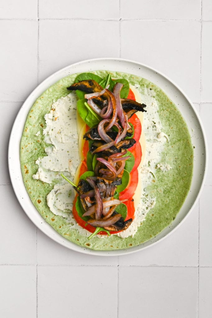 adding marinated and roasted portobello mushrooms and red onion to sandwich wrap