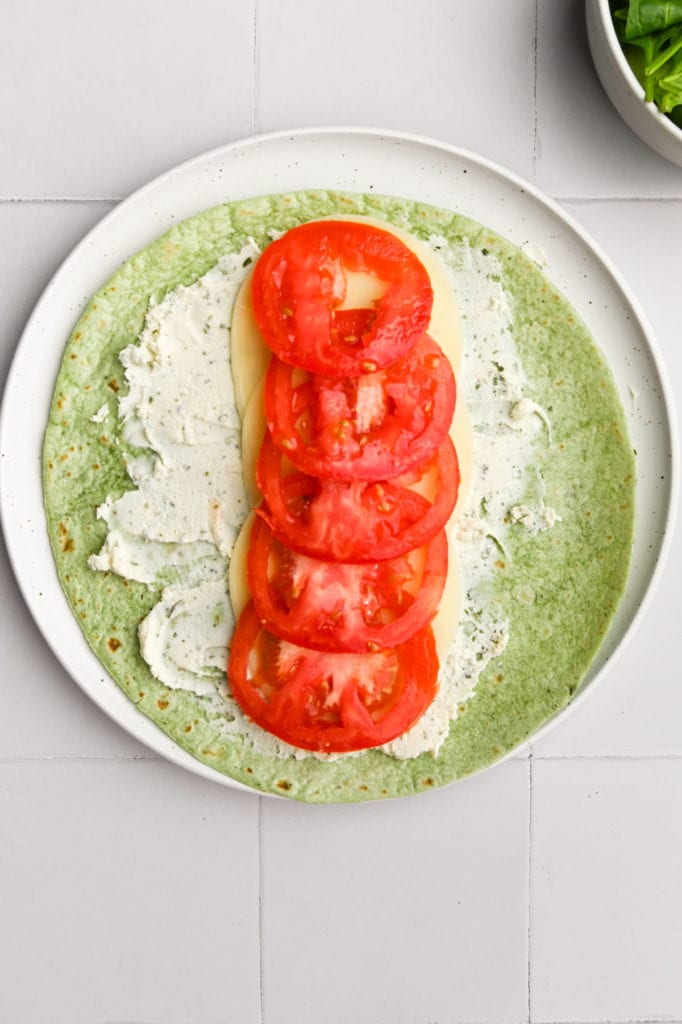 adding sliced tomatoes to portobello mushroom wrap