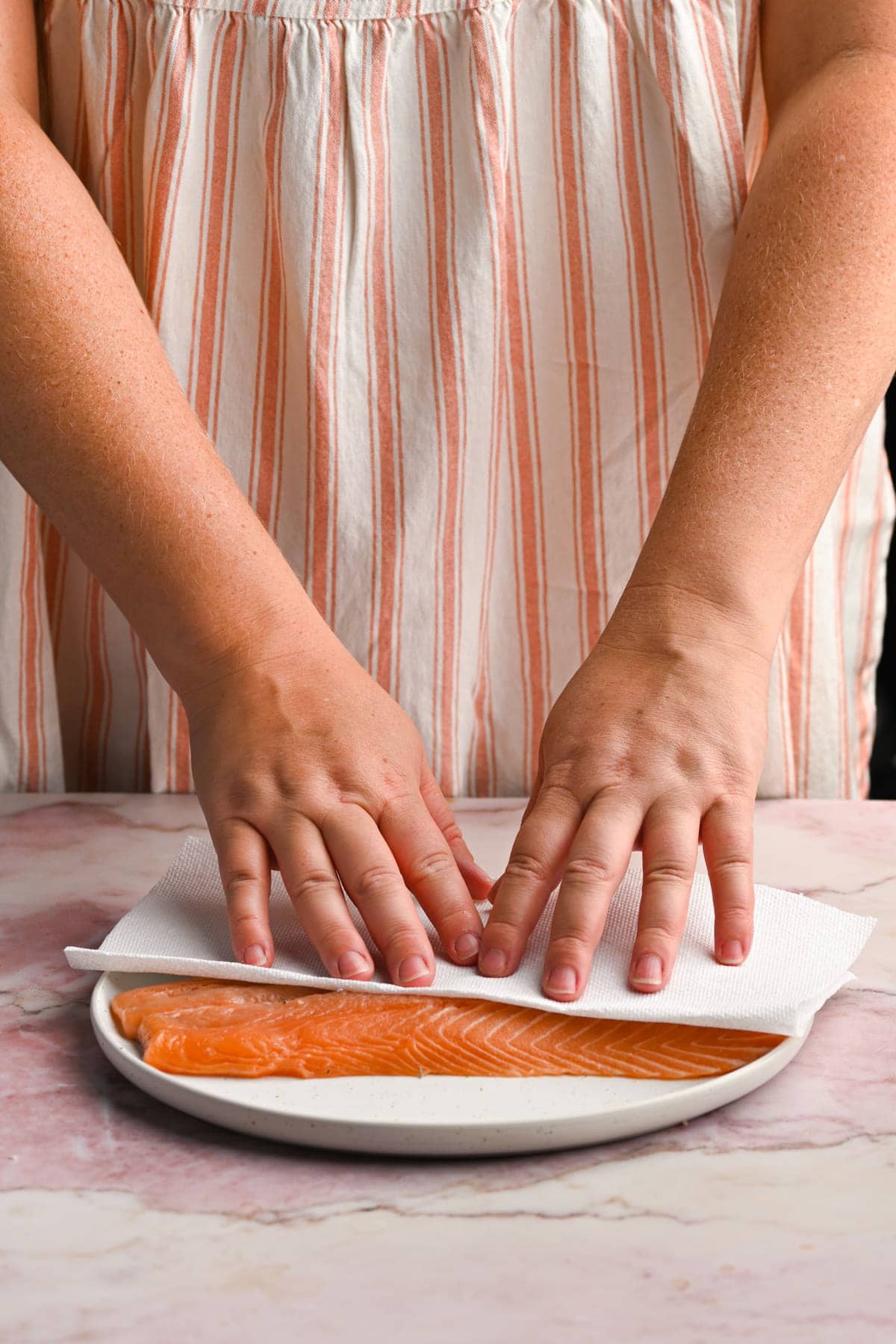 patting salmon dry with a paper towel