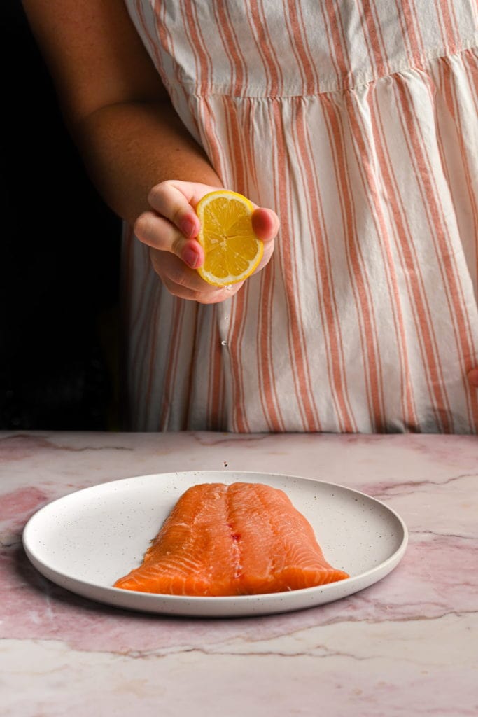 squeezing lemon juice onto salmon