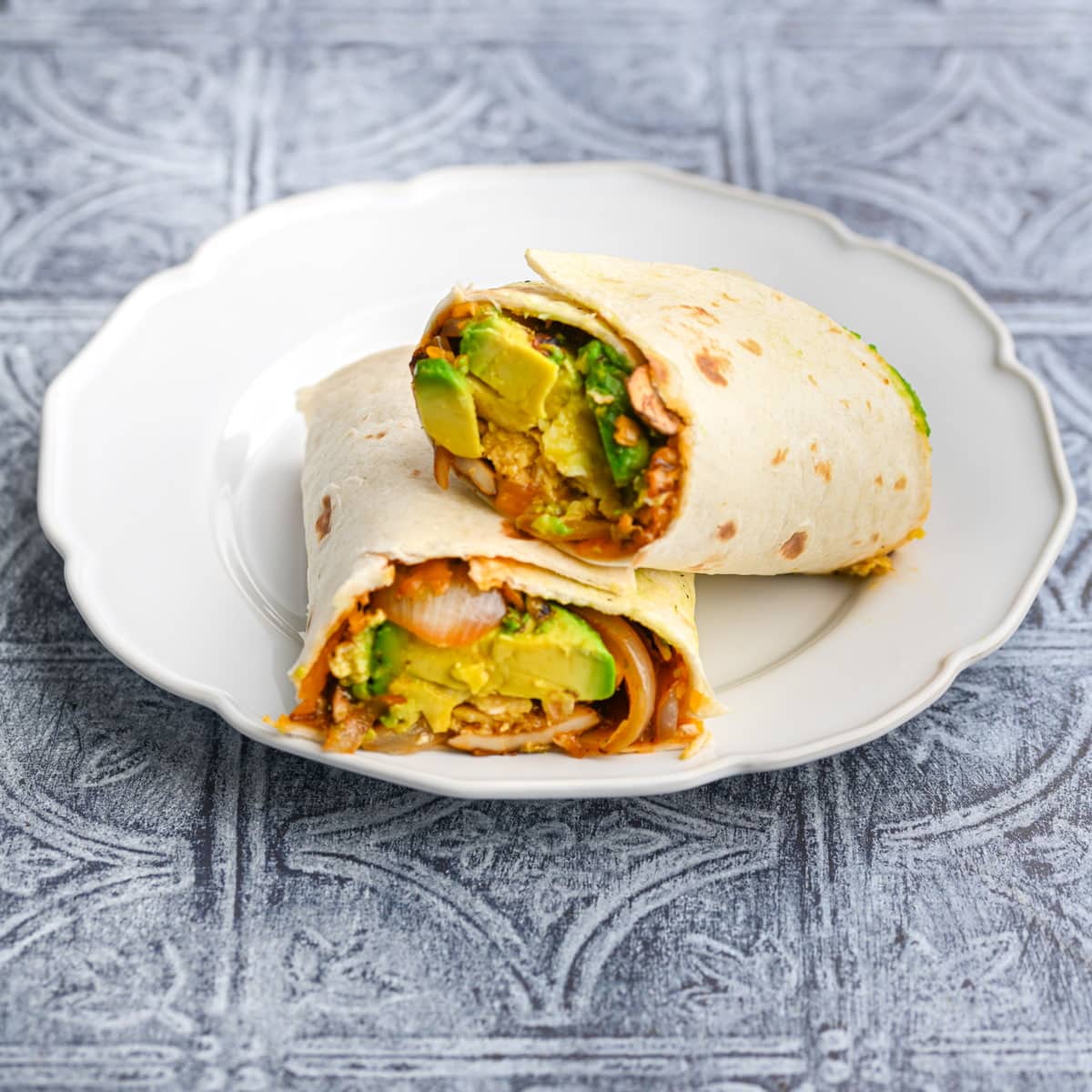 vegetarian breakfast burrito cut in half with one half resting on the other