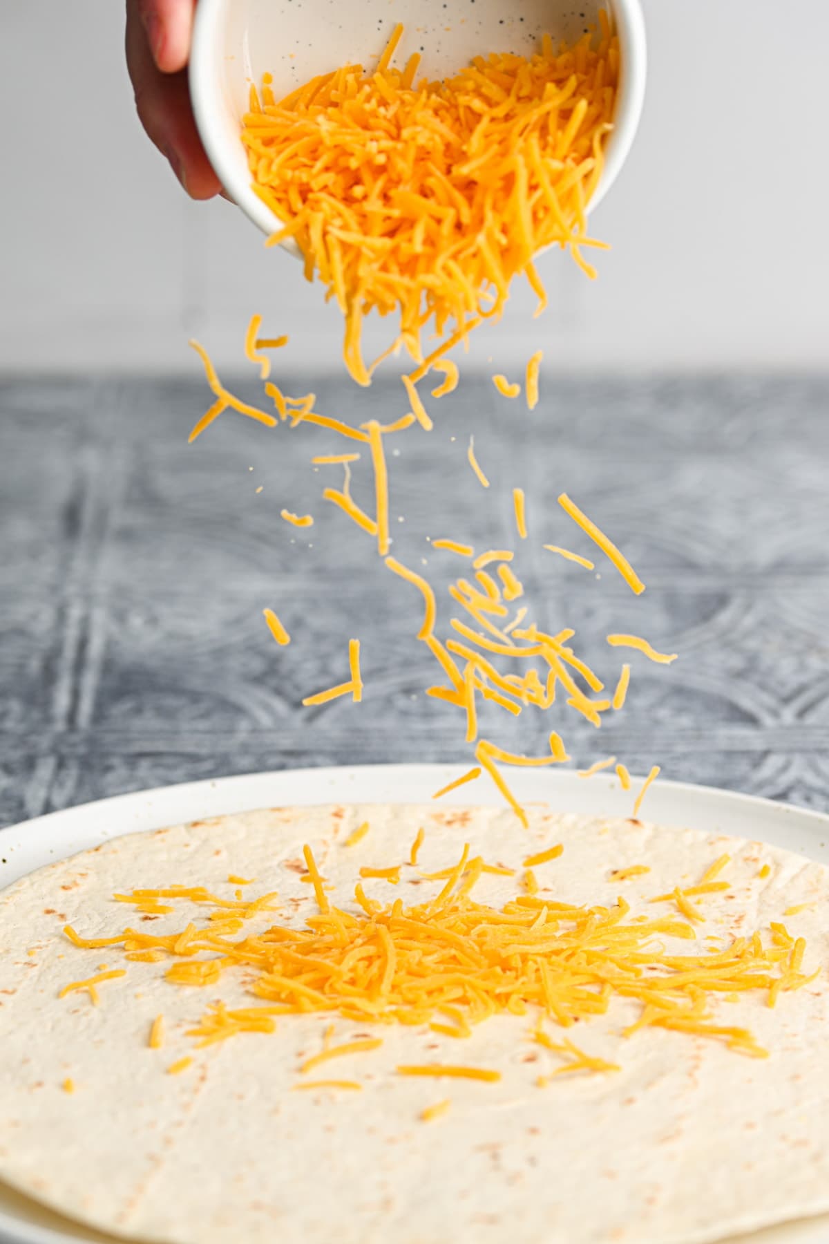 Adding cheese to a tortilla.
