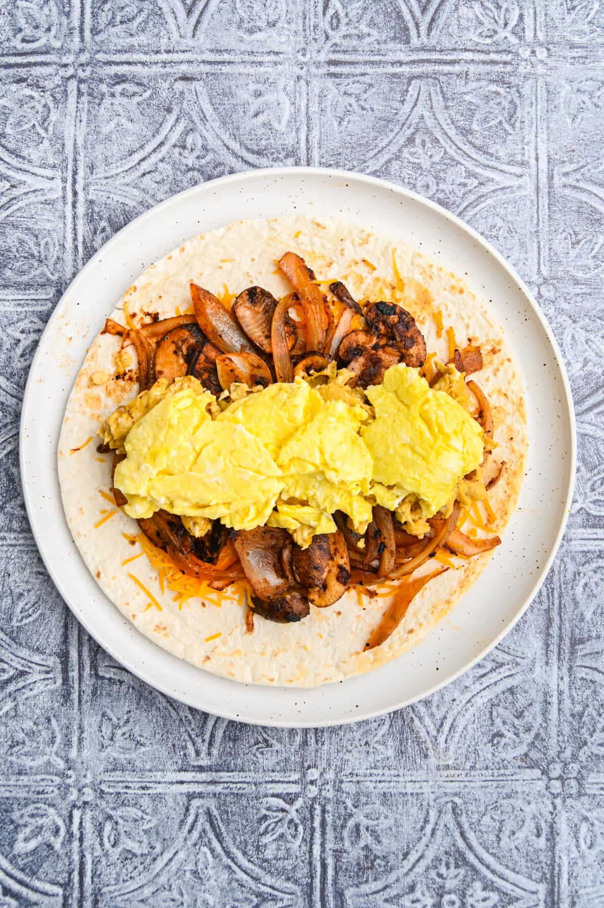 adding scrambled egg to vegetarian breakfast burrito