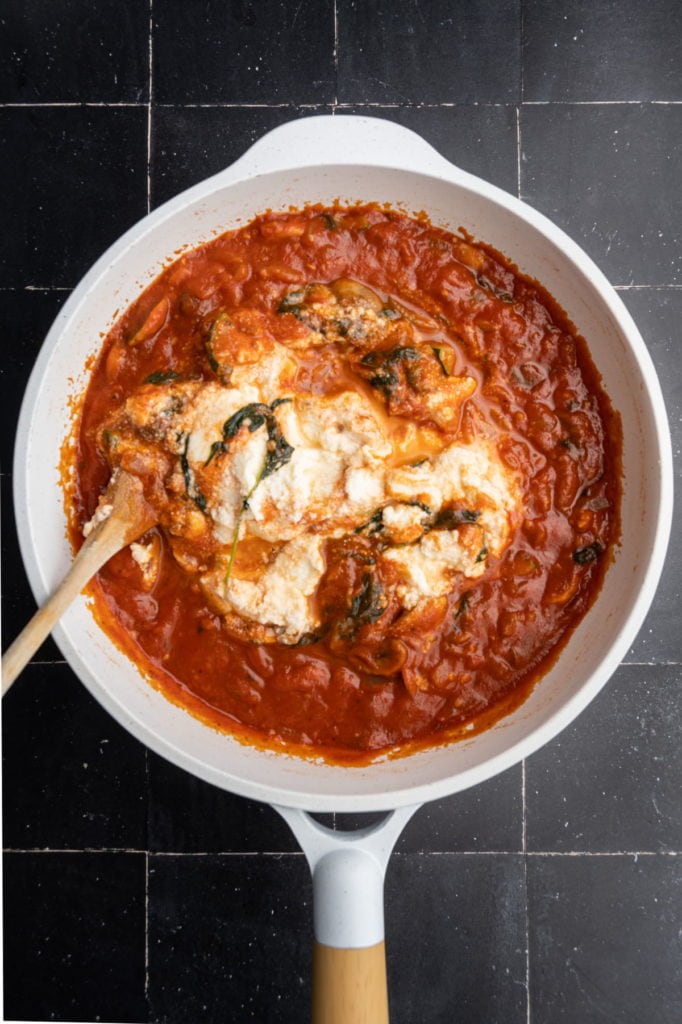 adding ricotta to veggie-packed sauce