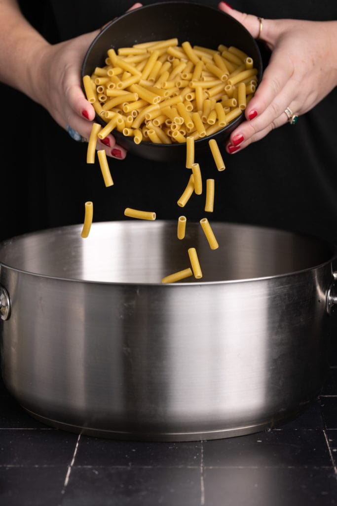 adding ziti to large pot with boiling water