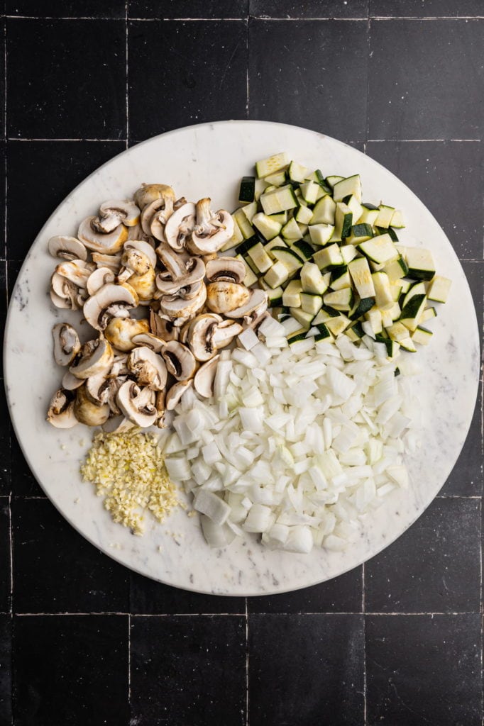 slicing mushrooms, dicing zucchini and onion, and mincing garlic
