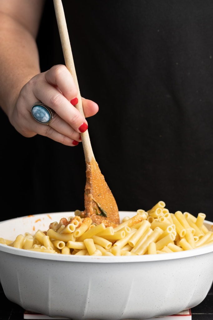 stirring ziti into vegetable sauce to coat