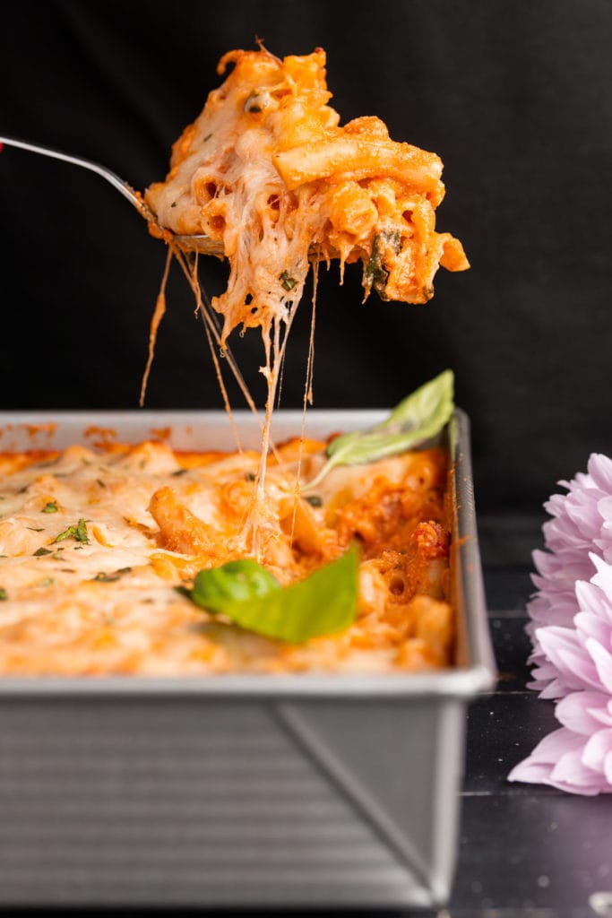serving up a heaping scoop of baked ziti to show cheesiness 