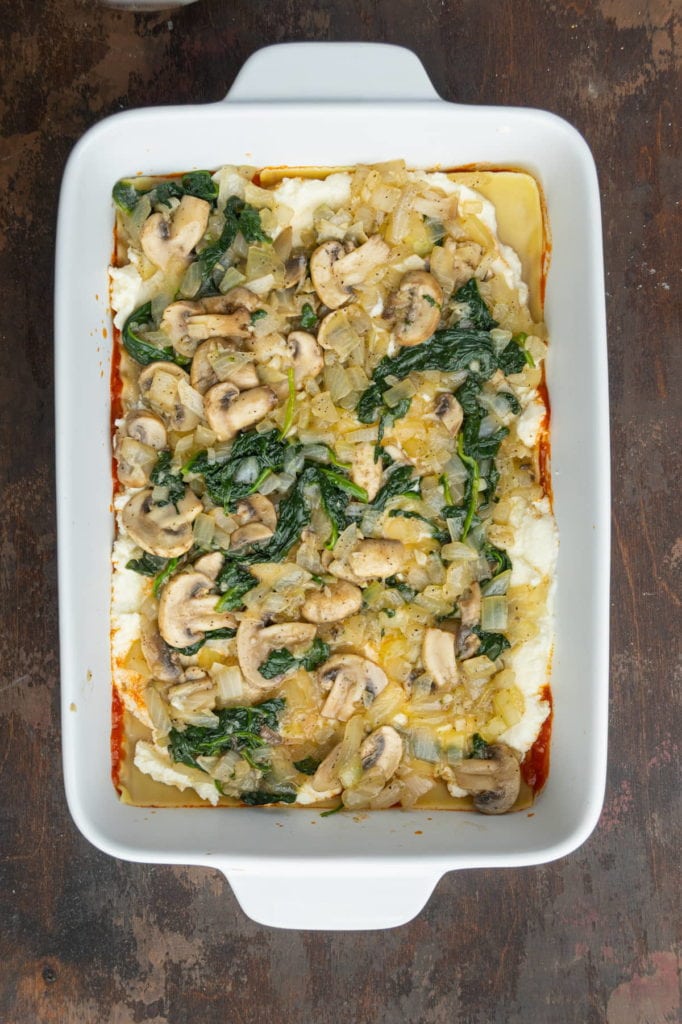 Layer of cooked vegetables on top of layer of ricotta in meatless lasagna.
