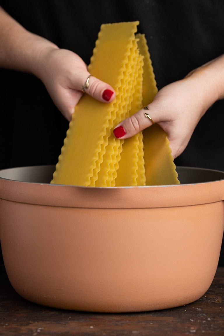 adding lasagne to boiling water to cook