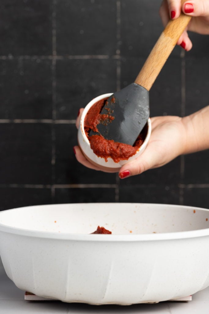 adding tomato paste to saucepan to make meatless spaghetti sauce