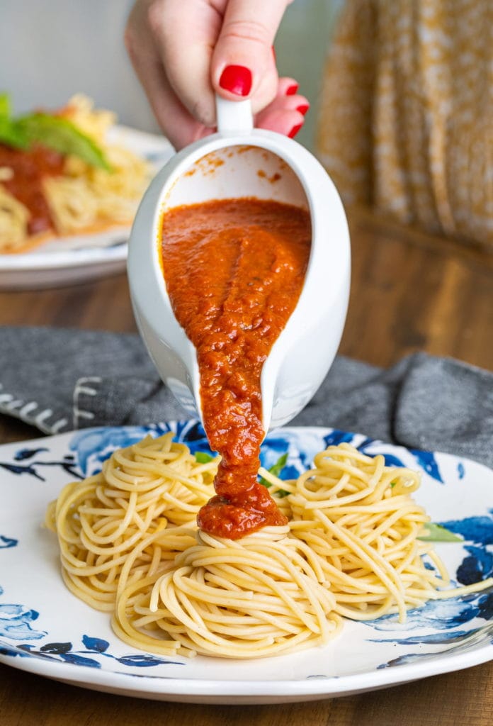 pouring meatless spaghetti sauce over top plated spaghetti