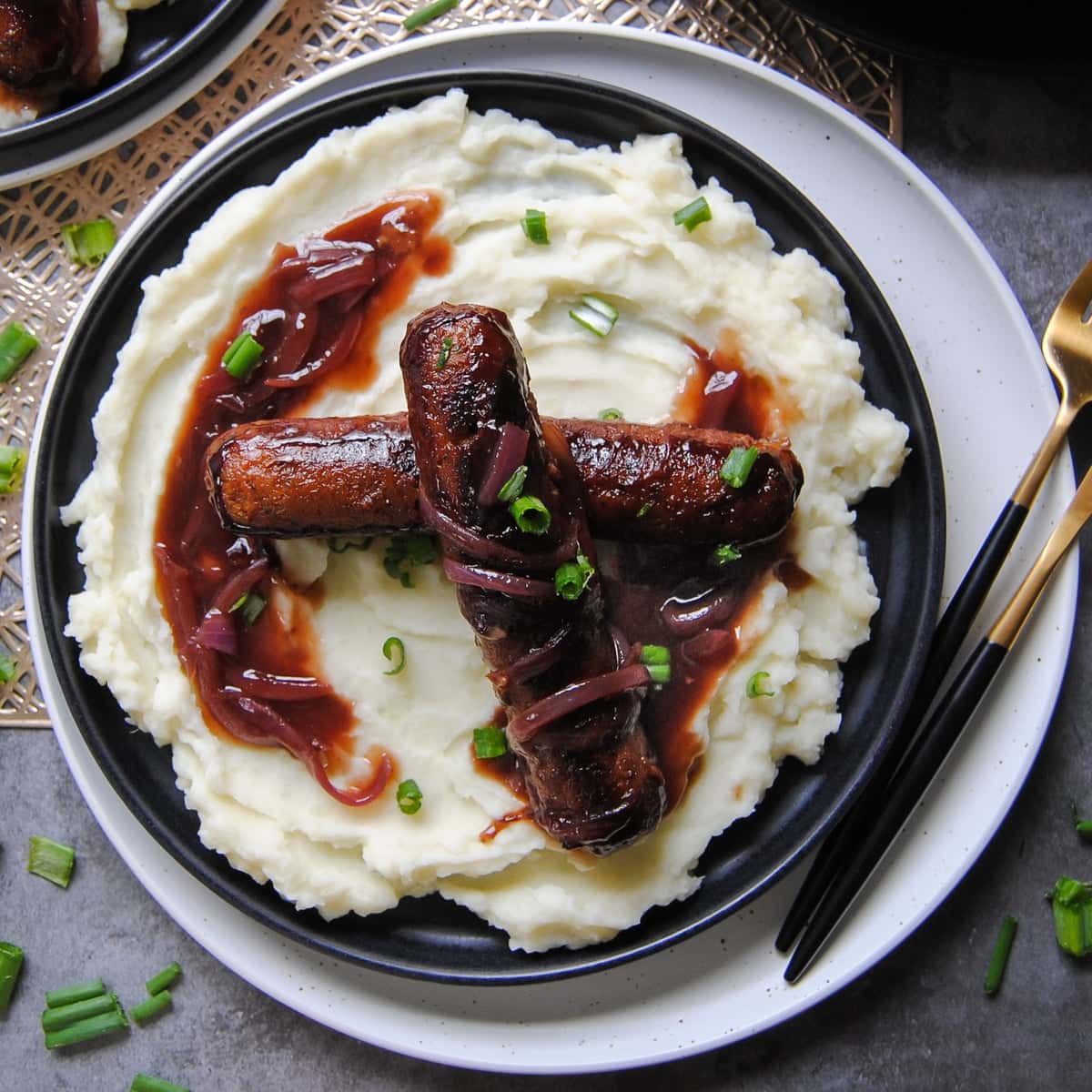 overhead view of bangers and mash on a black plate