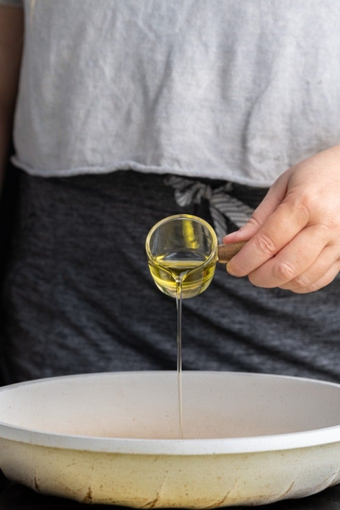 pouring olive oil into a pan to get hot