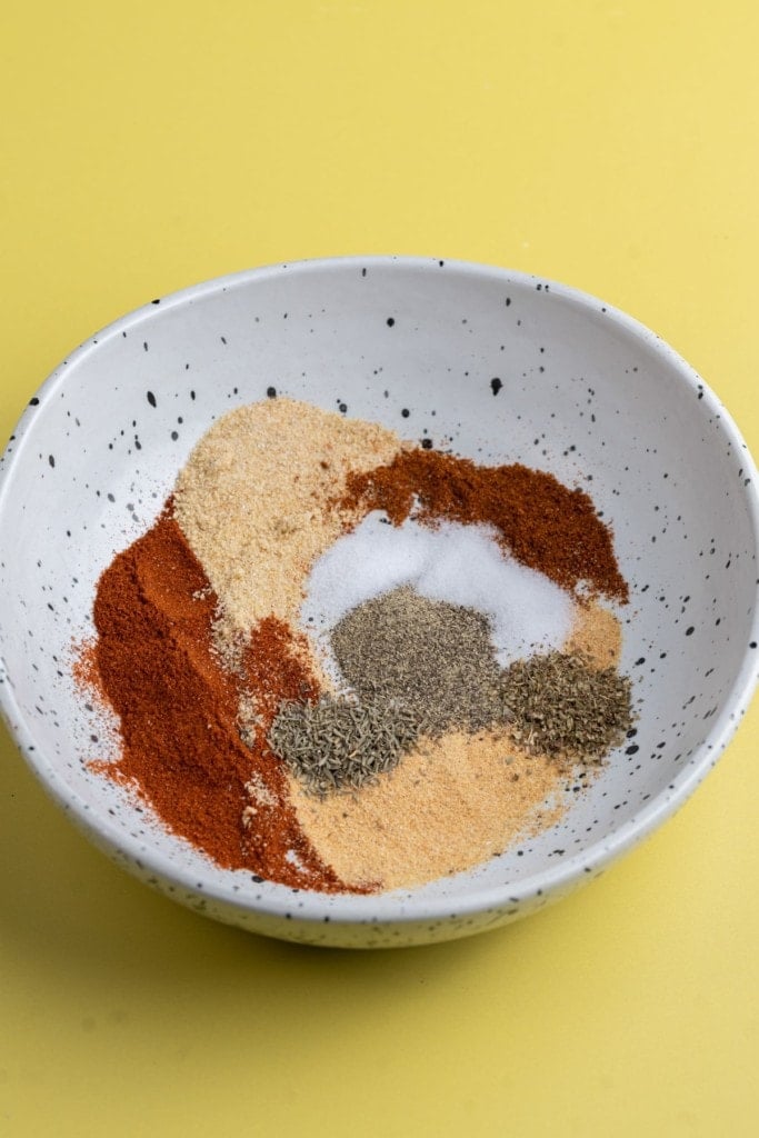 adding spices to a bowl to make blackening seasoning