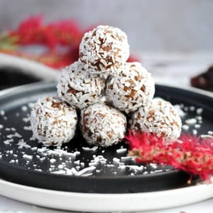 a pyramid of coconut covered energy balls on a black plate