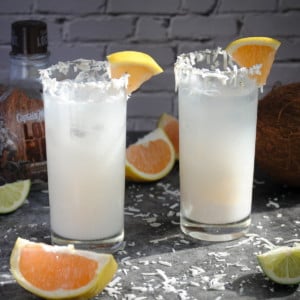 2 highball glasses with Coconut Daiquiri with Grapefruit Juice, garnished with orange slices