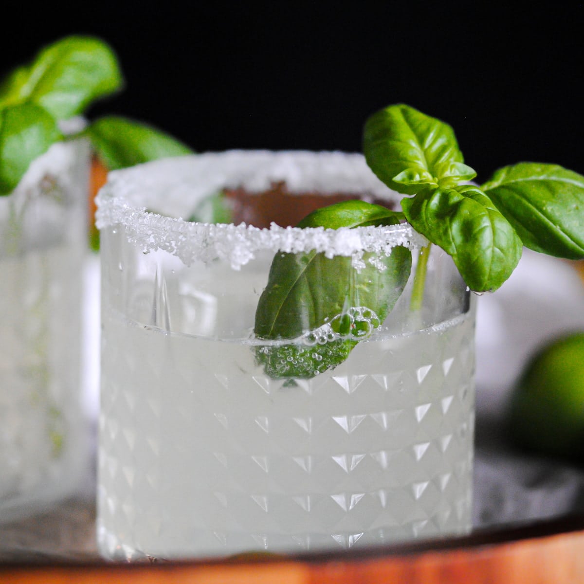 close up of a tumbler of Limoncello Cocktail with basil garnish and a salted rim