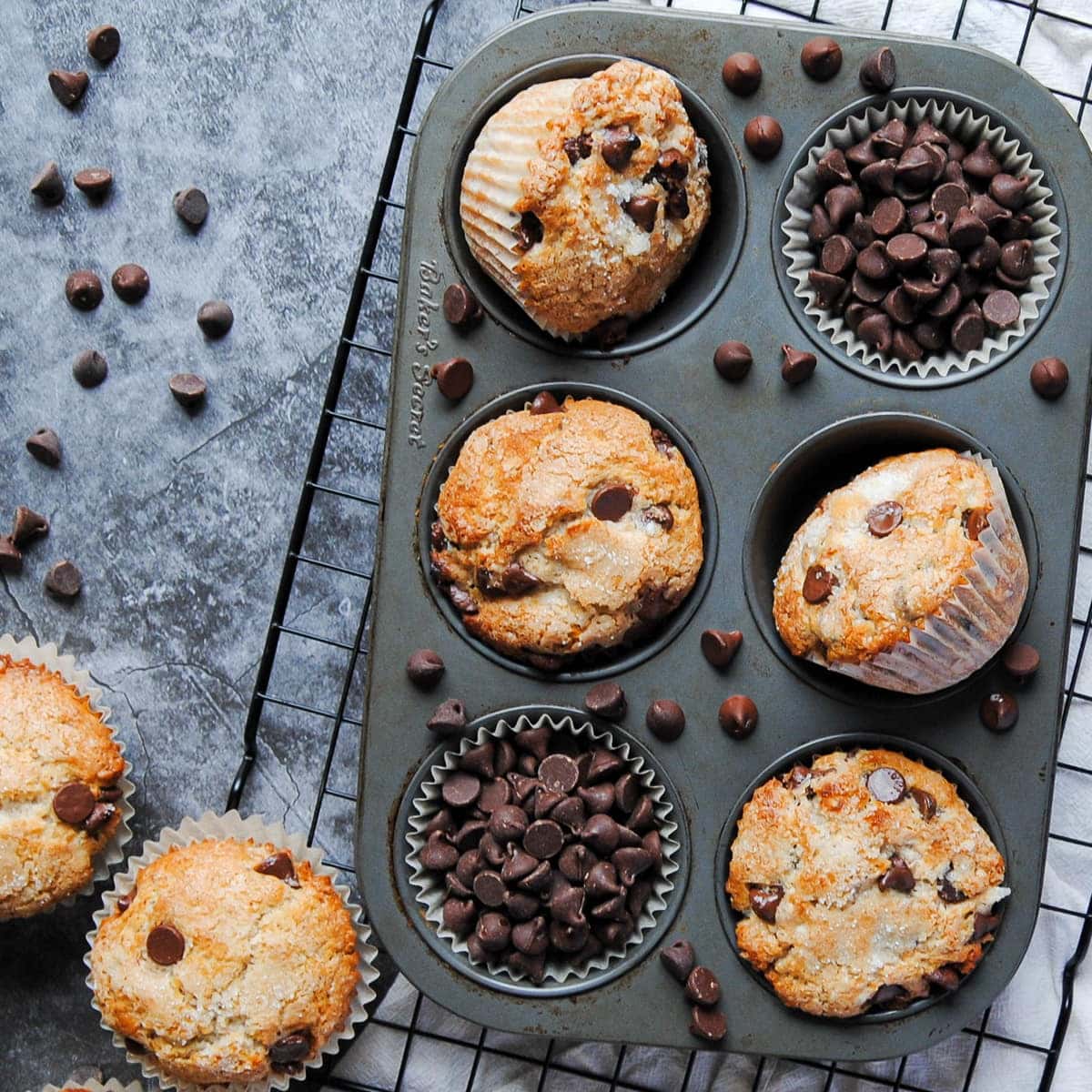 Overhead view of One-Bowl Chocolate Chip Muffins styled in a muffin tin with some slots filled with chocolate chips