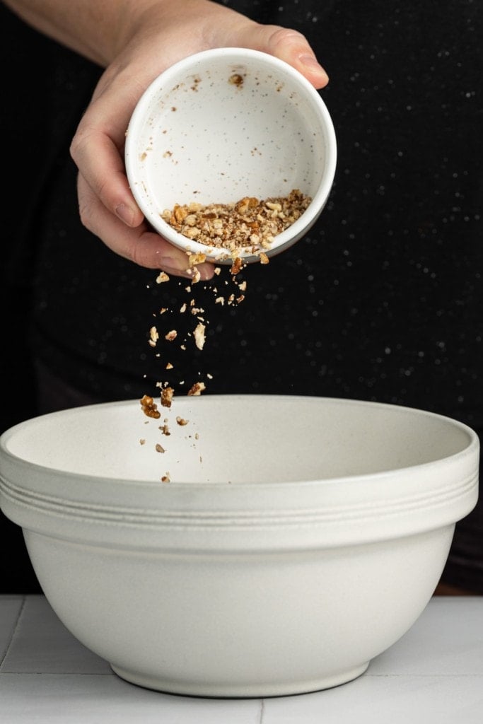 pouring crushed pecans into mixing bowl to make crust