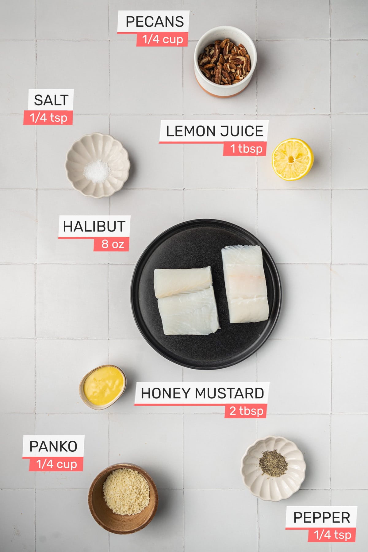 Overhead picture of all ingredients needed for Pecan Crusted Halibut on a white tile background - Pecans, Salt, Lemon Juice, Halibut, Honey Mustard, Panko, Pepper
