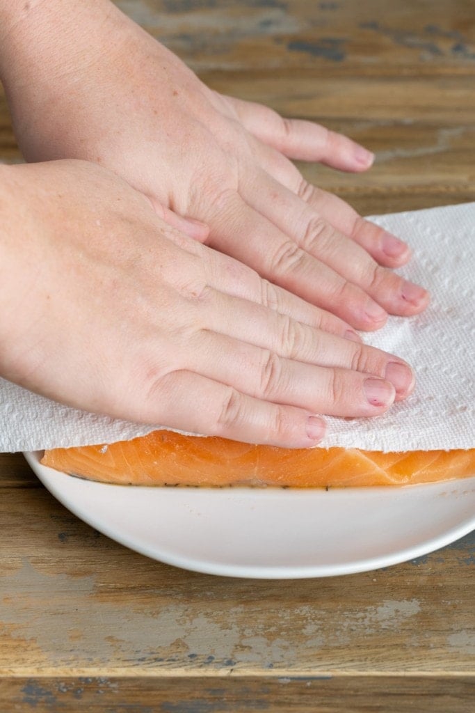 patting salmon dry with paper towel to reduce excess moisture