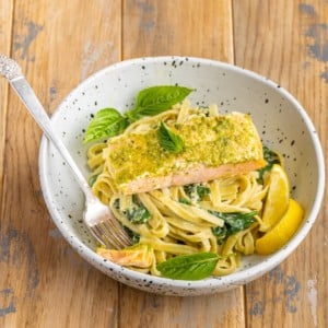 pesto butter salmon served on top of creamy pasta