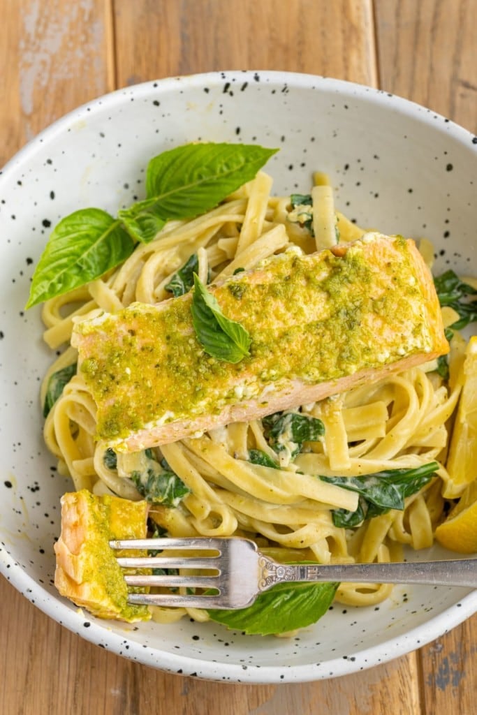 close up of pesto butter salmon over pasta with a forkful