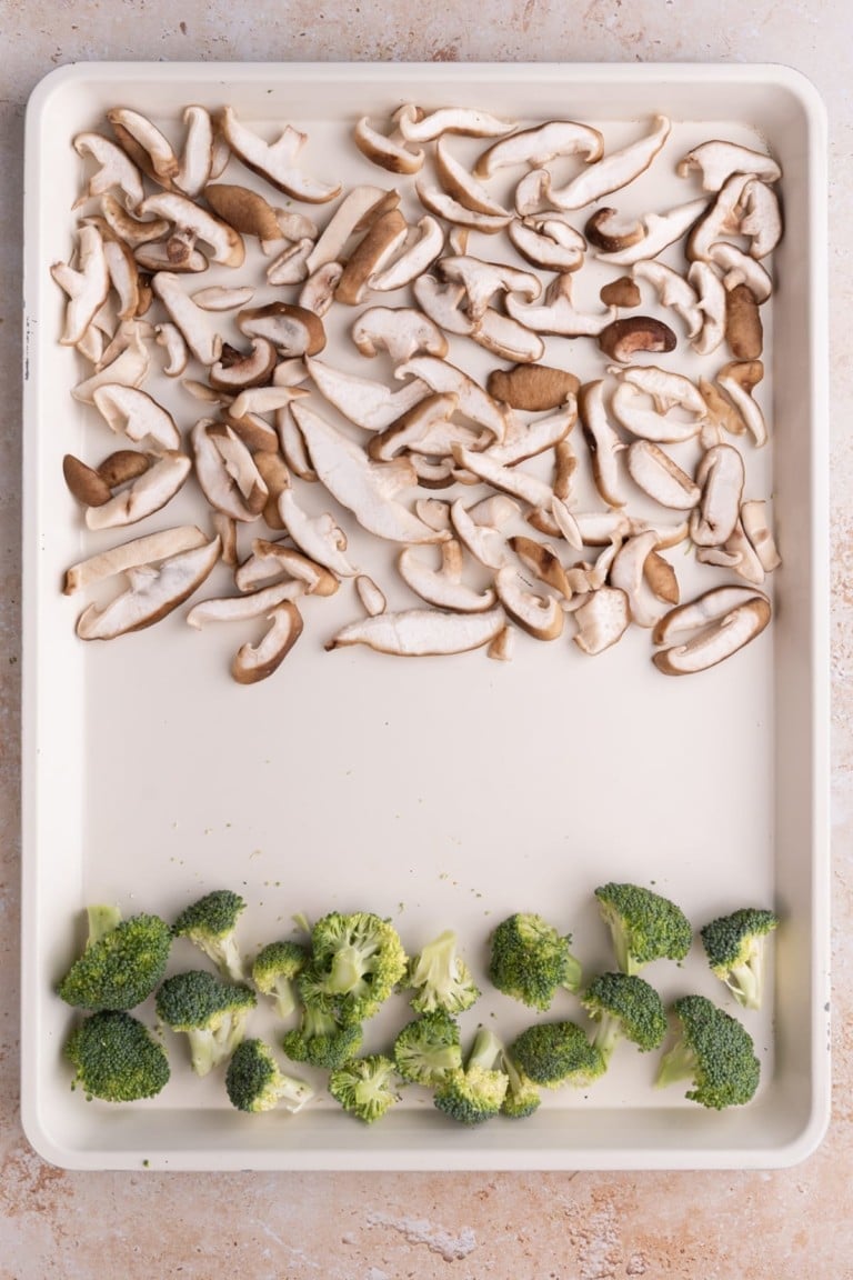 Adding broccoli and mushrooms to large baking sheet